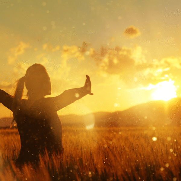 woman with open arms facing the sun at sunset time