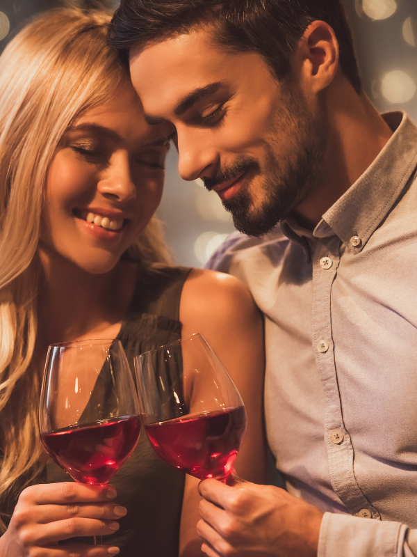 romantically close to each other couple holding wine glasses