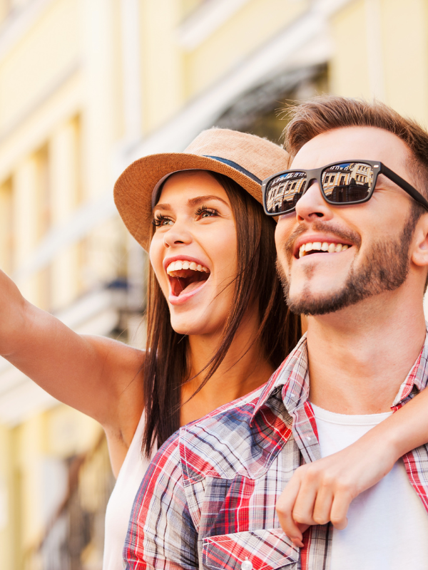 woman hugging a man from behind and both smiling at something she points at