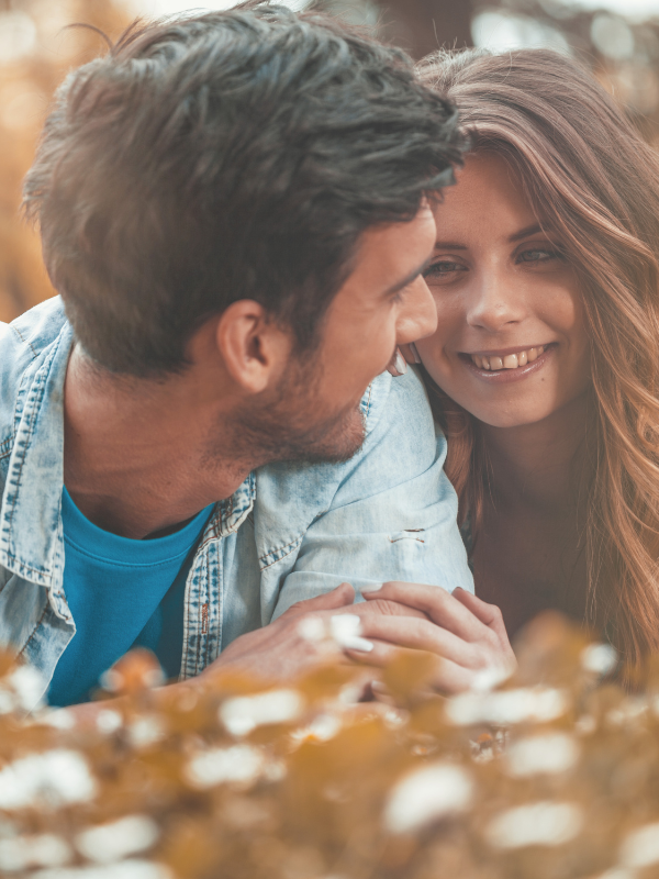 man and woman laying on the grass and she looks with affection towards him