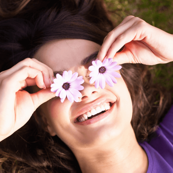 woman-smiling-playing-with-flowers