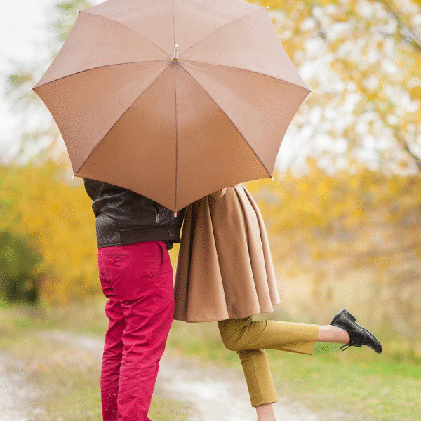 couple kiss behind an umbrella
