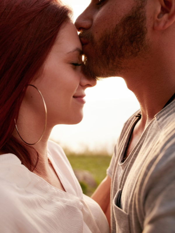 man kissing woman forehead