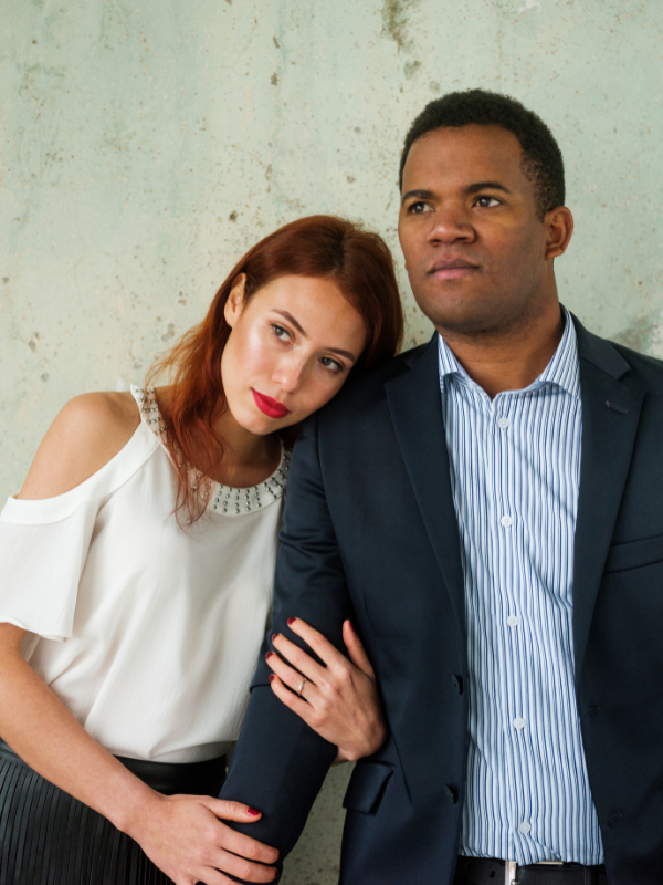 woman holding mans arm as he looks disturbed