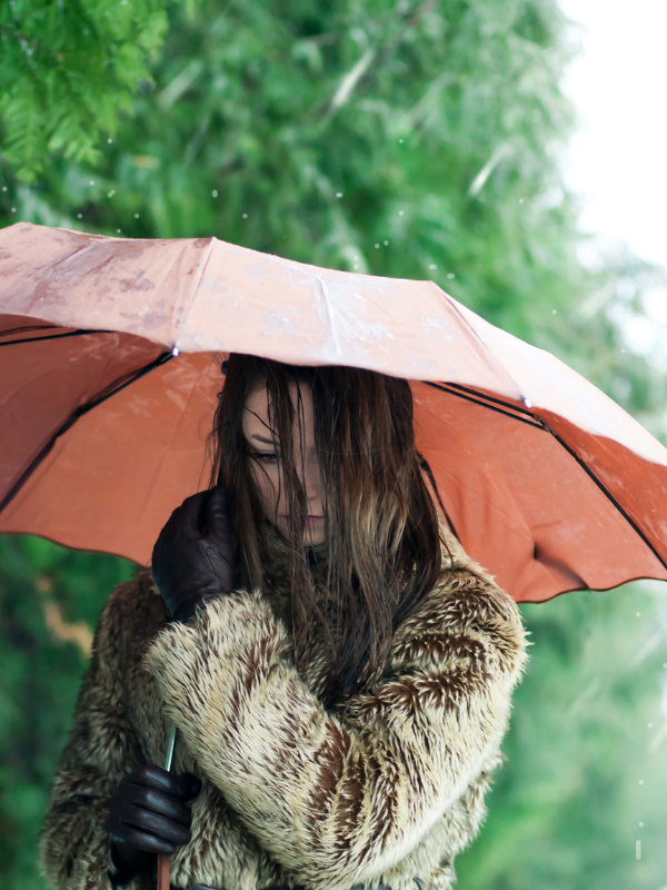 woman with low self esteem with umbrella under the rain